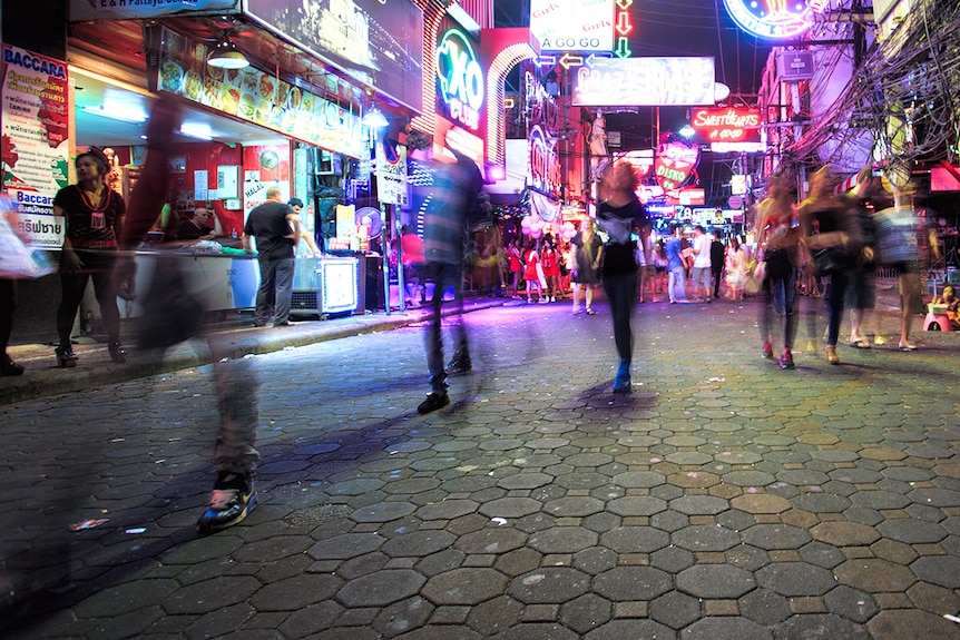Blurred shot of people walking through a neon-lit street at night