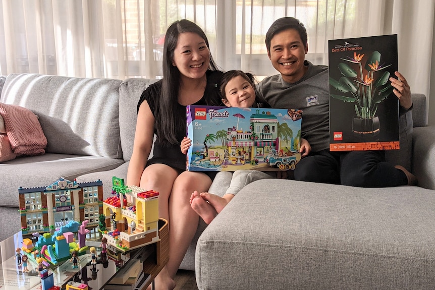 Members of the Ong family (Sue, Laura and Jay) smiling for a photo and holding up games for a story about lockdown hobbies.