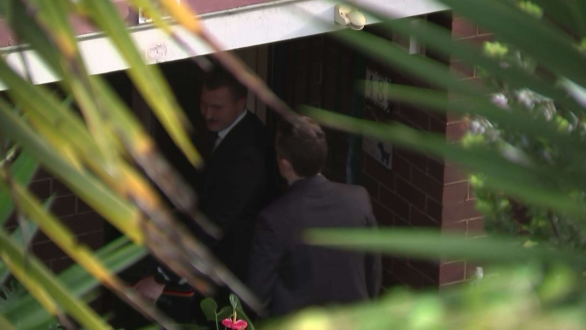 Two men in suits entering home 