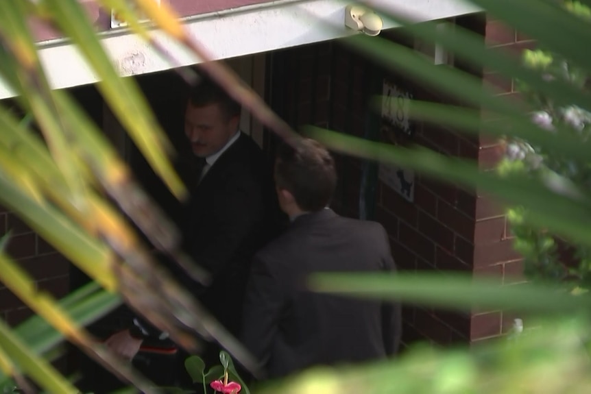 Two men in suits entering home 