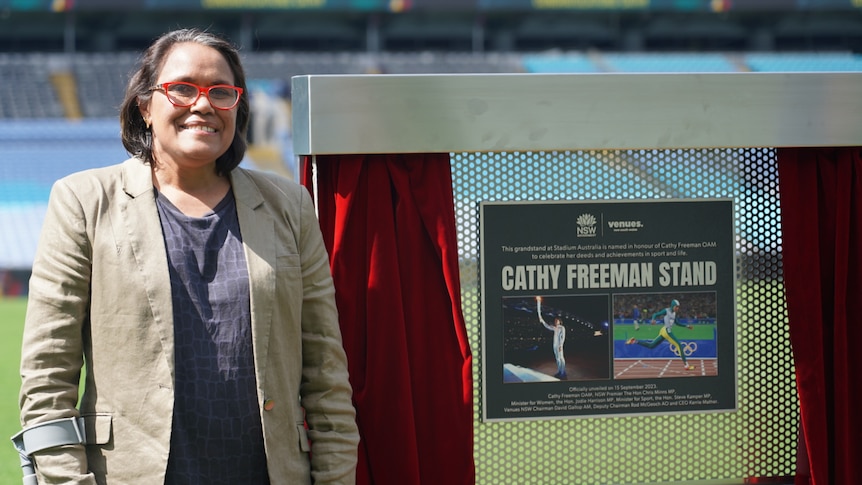 Cathy Freeman stands in front of a sign
