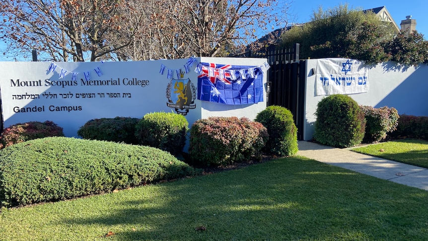The entry to Mount Scopus Memorial College, a rendered white fence with an Australian and Jewish flag