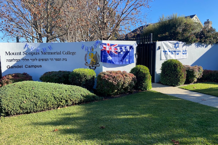 The entry to Mount Scopus Memorial College, a rendered white fence with an Australian and Jewish flag