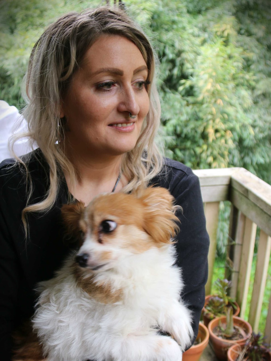 A woman holding a small dog.