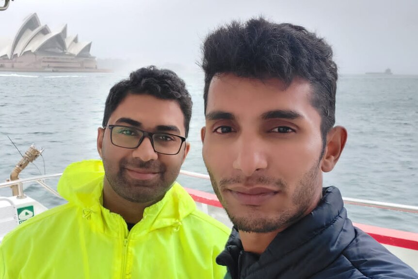 two men on a boat with the opera house in the background