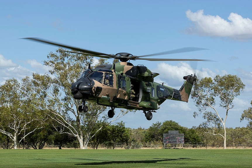 A helicopter comes into land on a grass field.