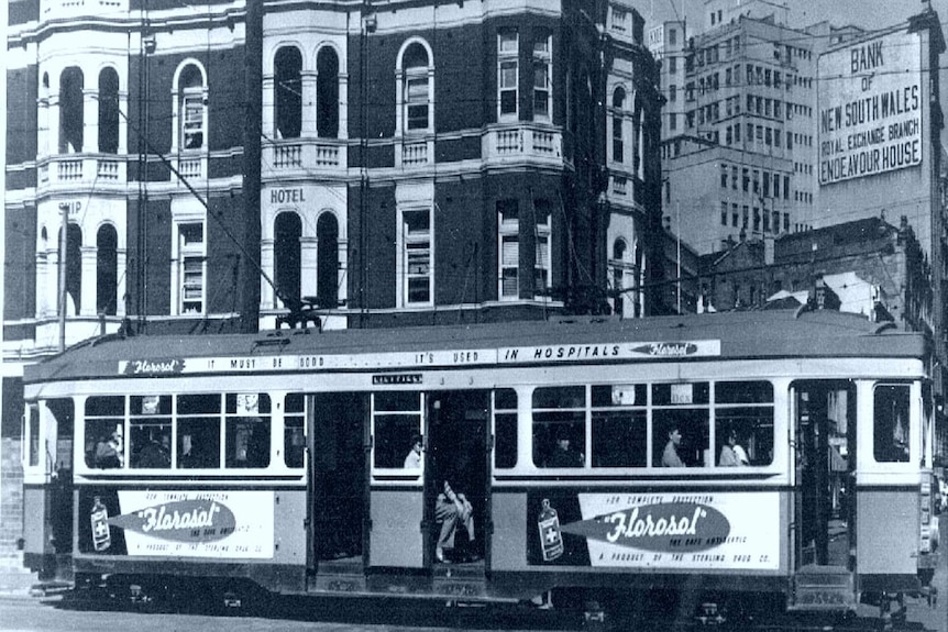 A black and white picture of a tram bearing a Florosol disinfectant ad in front of old buildings