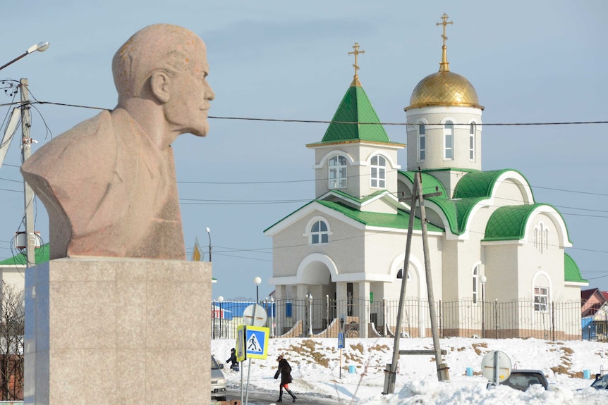 A bust of Soviet state founder Vladimir Lenin is seen in front of the Holy Trinity Cathedral