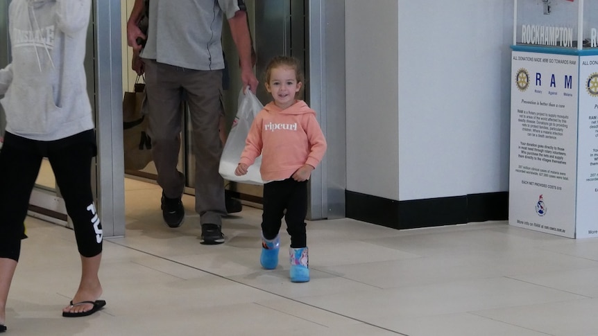 Three-year-old Nevaeh Austin smiles as she arrives at Rockhampton airport with her family.