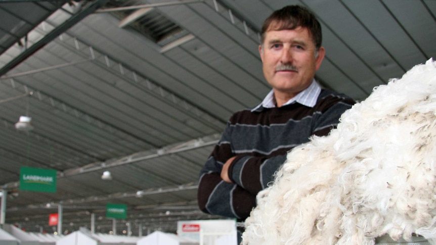 man standing next to wool bale