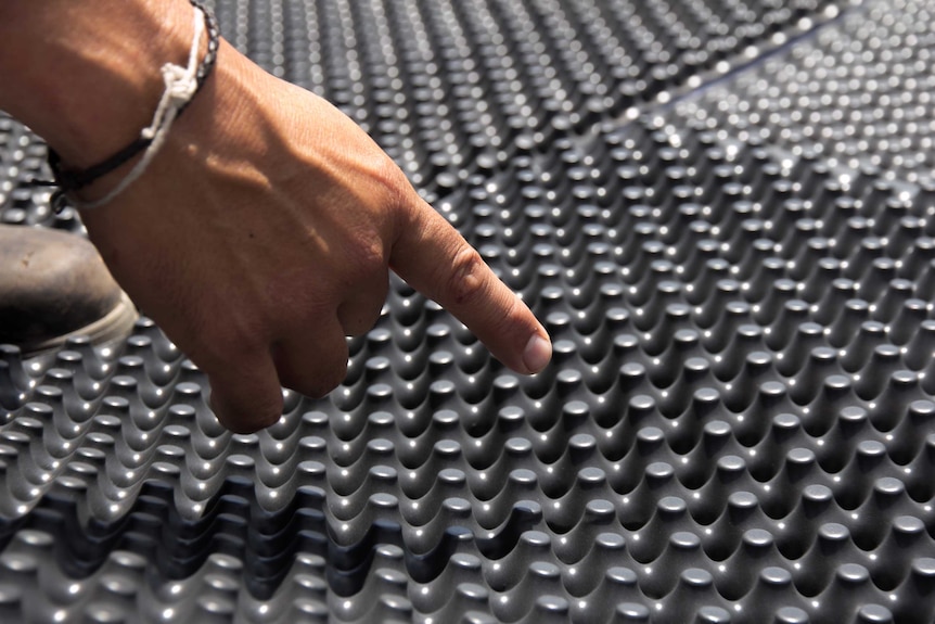 Close up of a man's hand pointing at egg-shell type drainage material