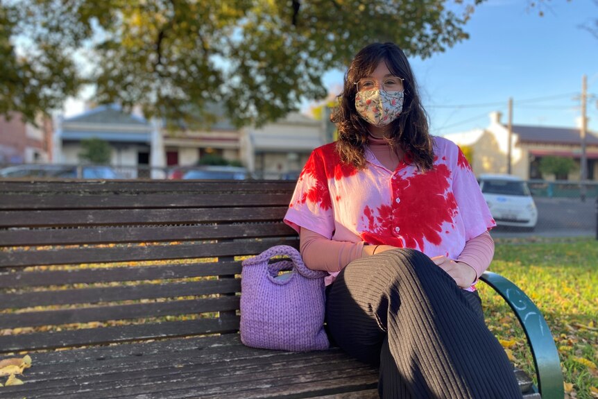 young woman with a covid mask on a park bench