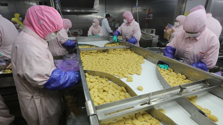 Employees work at a production line at the Husi Food factory in Shanghai