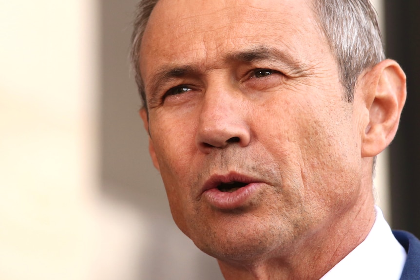 A close up of Roger Cook's face as he speaks at a media conference outside parliament