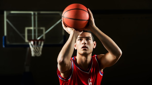 A man in a red singlet about to throw a basketball