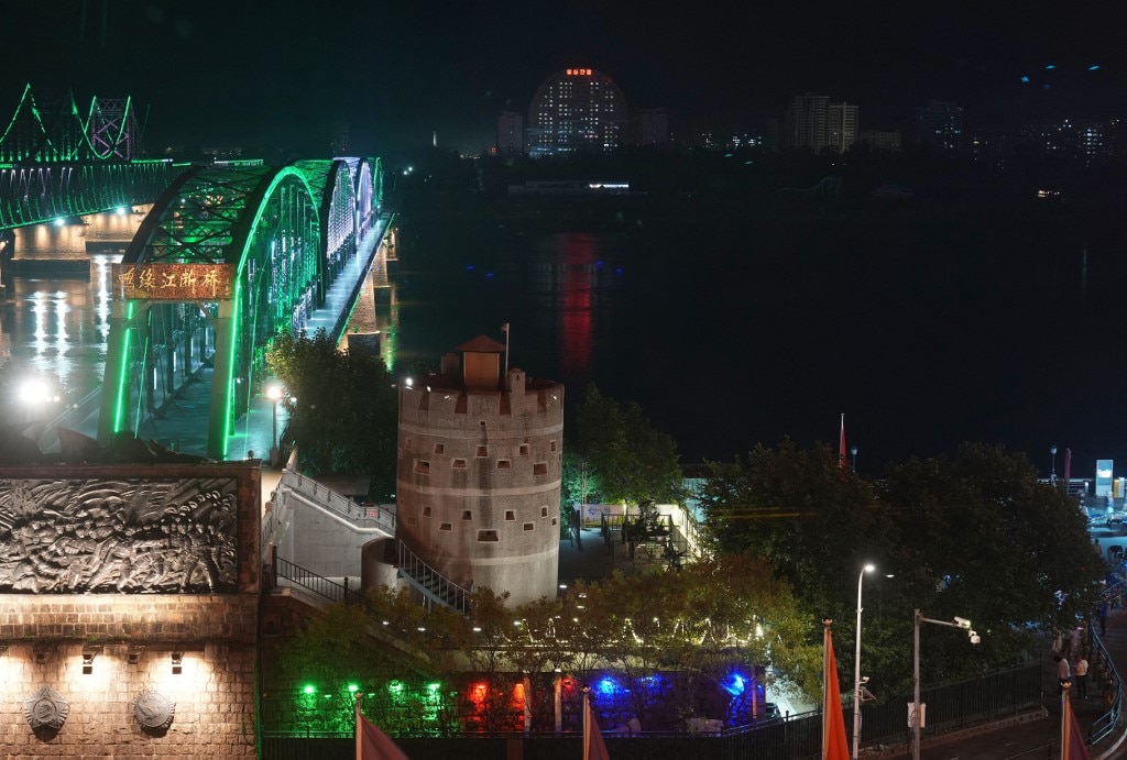 A brightly lit bridge met with darkness over the river.