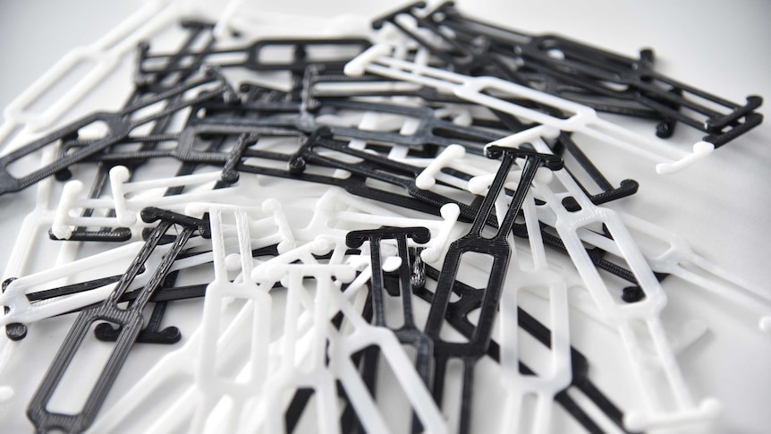A close up of black and white plastic clips used to secure a surgical mask around the back of the head