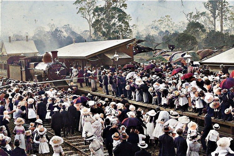 An image from 1913 of a crowd of people at a train station, as a steam locomotive arrives.