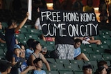 A protester holds up a banner against a proposed Hong Kong extradition law at a football match.