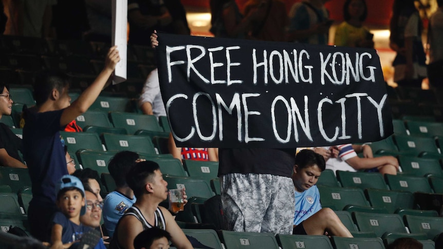 A protester holds up a banner against a proposed Hong Kong extradition law at a football match.