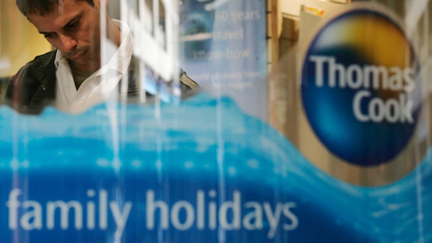A Thomas cook logo is emblazoned on a glass window, with a man standing in the background.