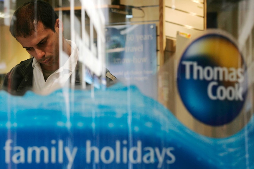 A Thomas cook logo is emblazoned on a glass window, with a man standing in the background.