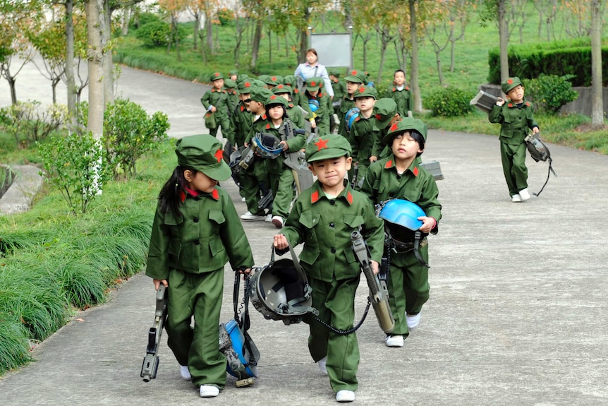 Little children dressed in Chinese military uniforms, carrying helmets