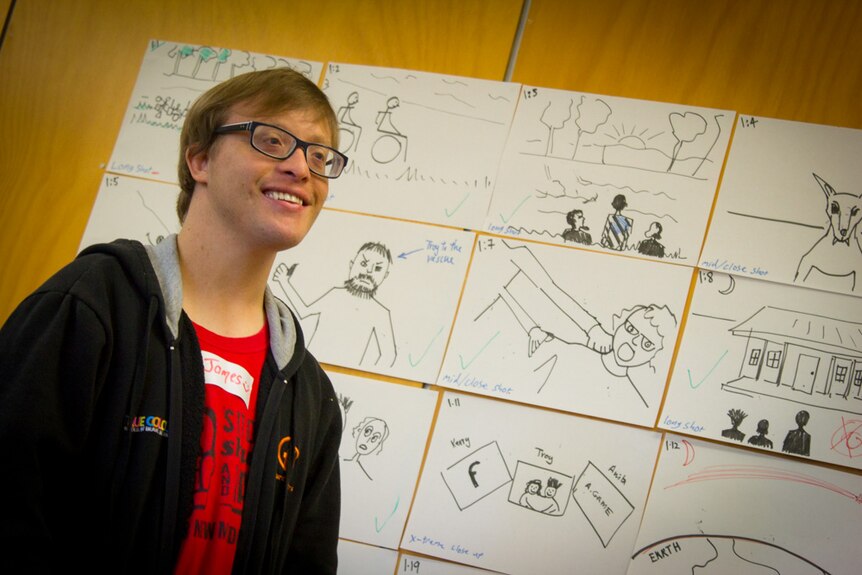 James Kurtze stands in front of a film storyboard.
