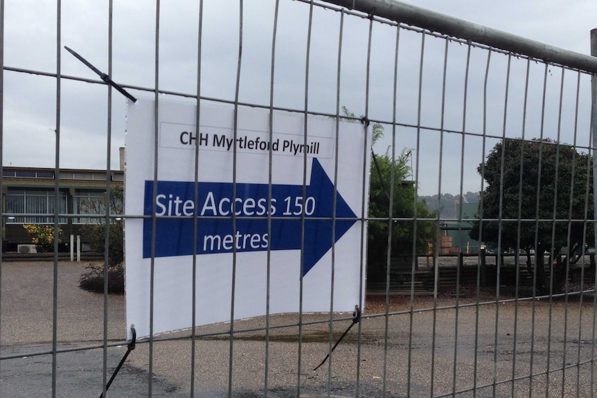 A sign is on a fence indicating the new entrance to the mill site
