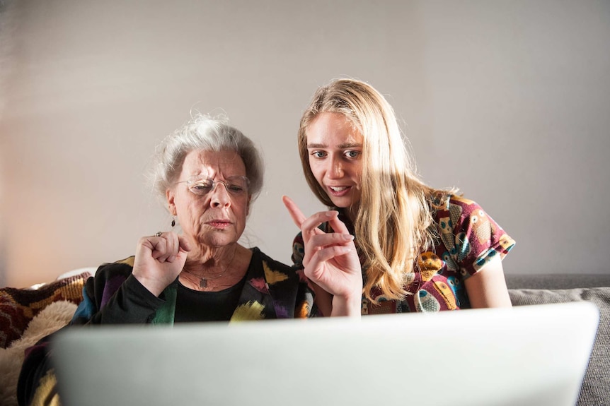 Young woman showing senior lady how to work a laptop.