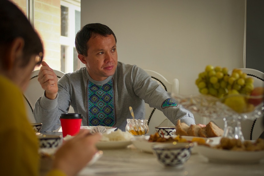 A young man at a table laden with food.