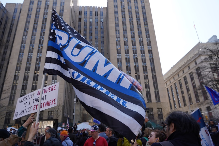 A supporter of Donald Trump waves a combined pro-Trump and 'thin-blue-line' flag. 