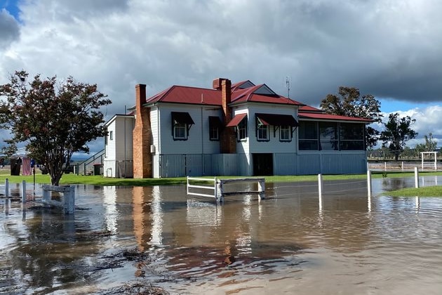 Floodwater surrounds a home with blue skies above.