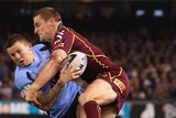 Todd Carney of the Blues is tackled by Brent Tate of the Maroons