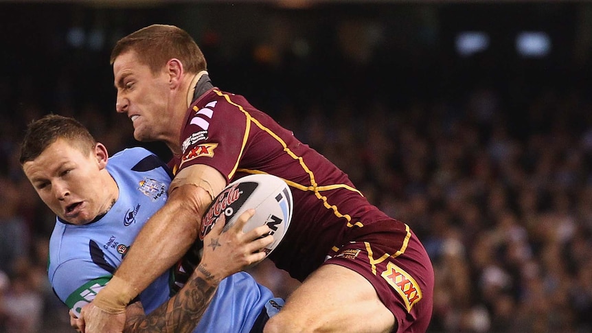 Todd Carney of the Blues is tackled by Brent Tate of the Maroons
