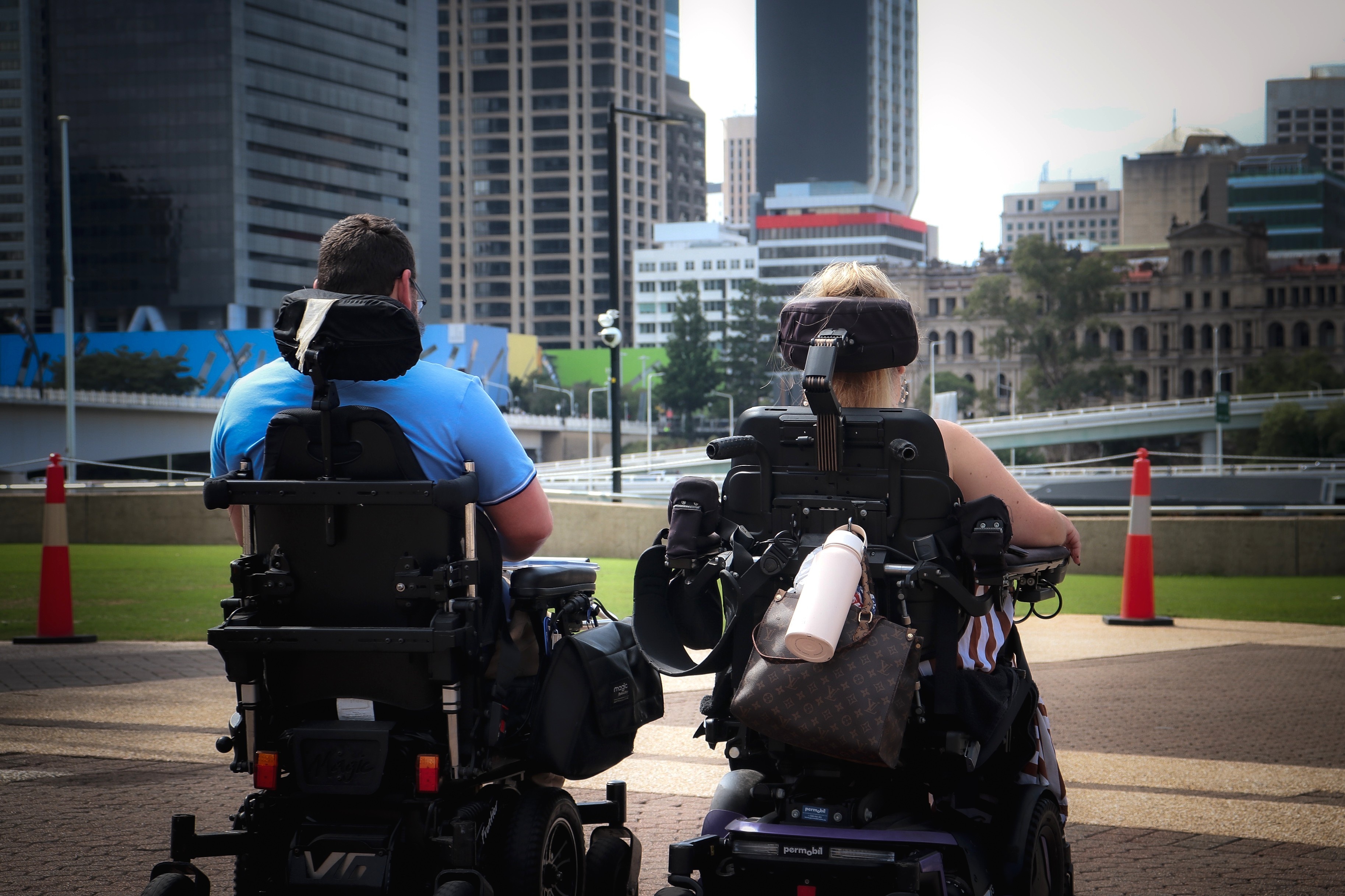 A man and a woman both in wheelchair looking towards the city