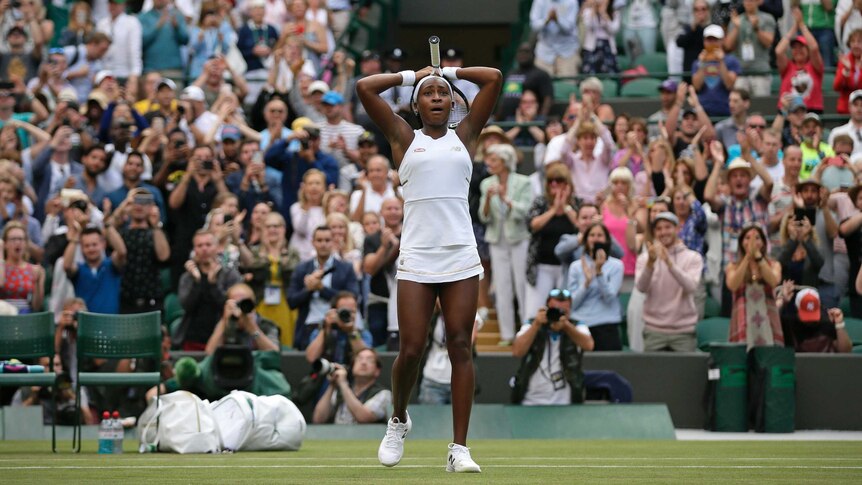 Cori Gauff holds her hands to her head as the crowd stands and applauds behind her