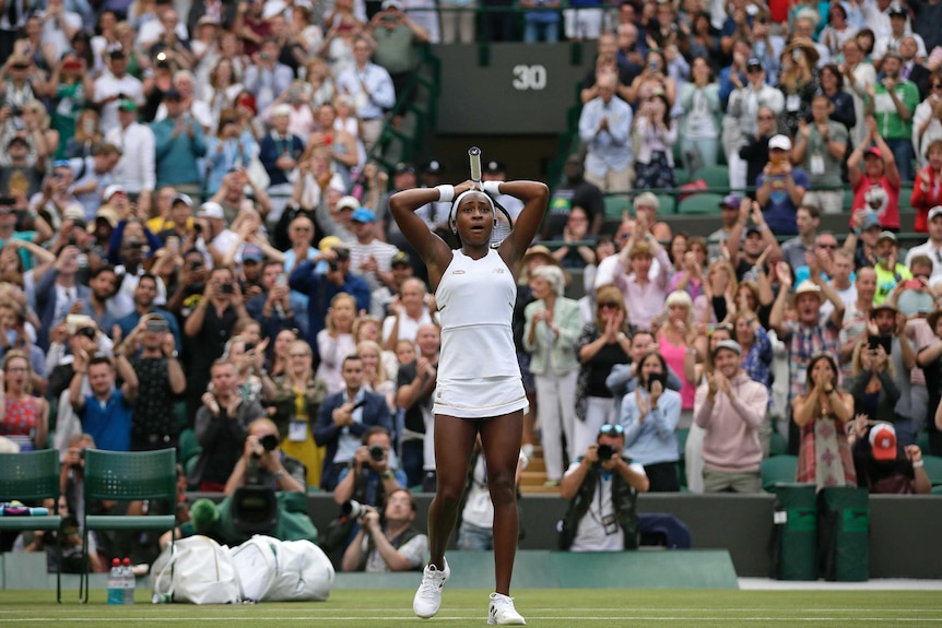 Cori Gauff holds her hands to her head as the crowd stands and applauds behind her