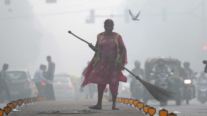 A street cleaner works in heavy smog in Delhi.