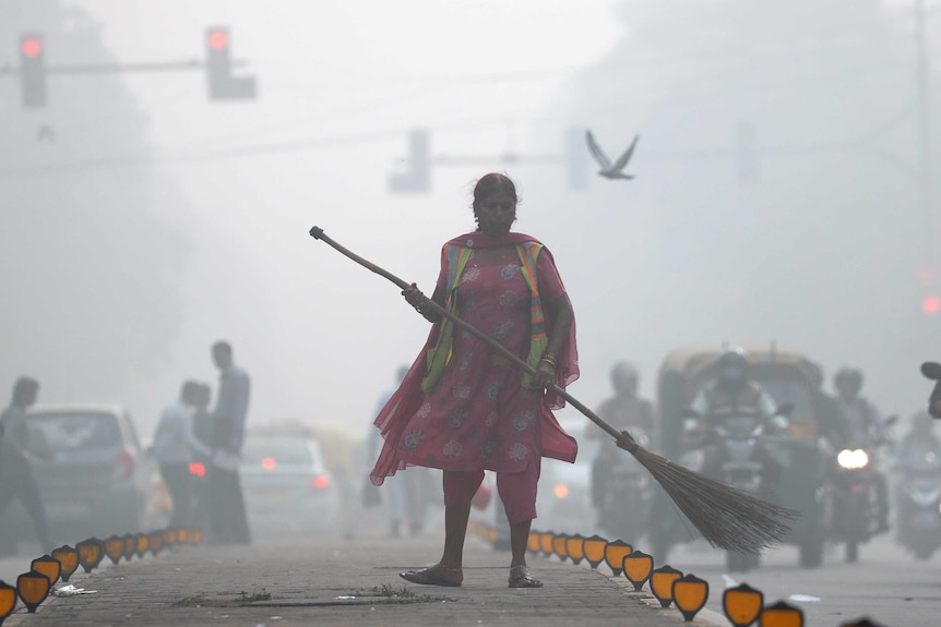 A street cleaner works in heavy smog in Delhi.