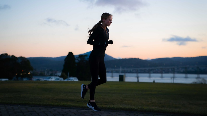 A young woman jogging at dawn.