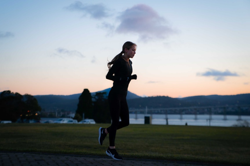 A young woman jogging at dawn.