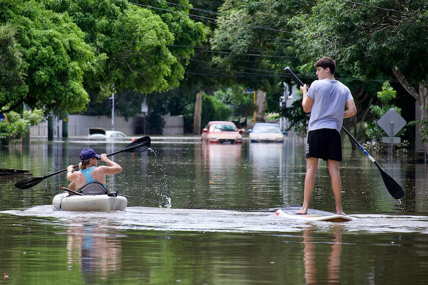 People paddle in dirty floodwaters in Milton, Brisbane