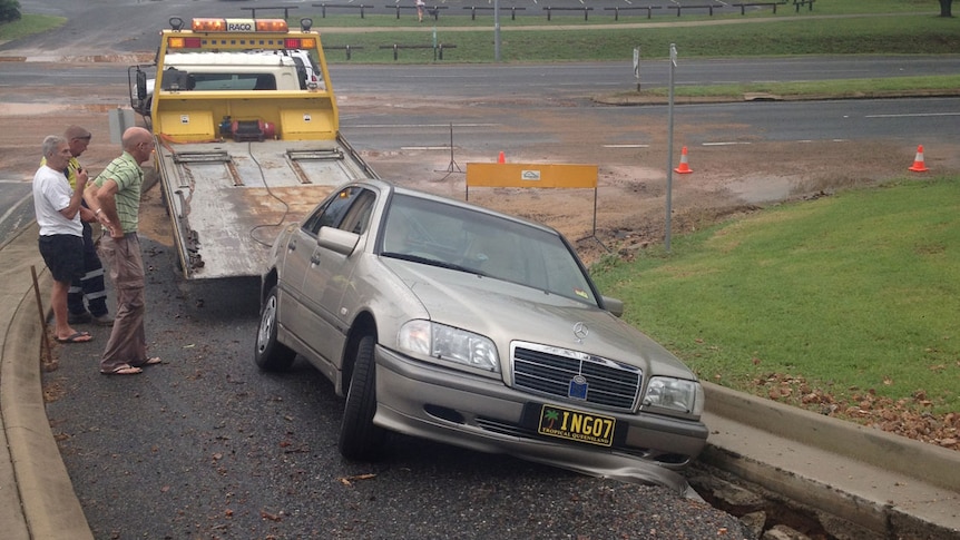 Car stuck in flood-damaged road in Yeppoon, north of Rockhampton in central Queensland on March 27, 2014