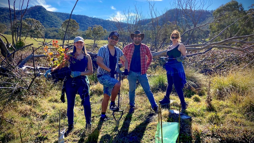 Four tree planting volunteers with work tools.