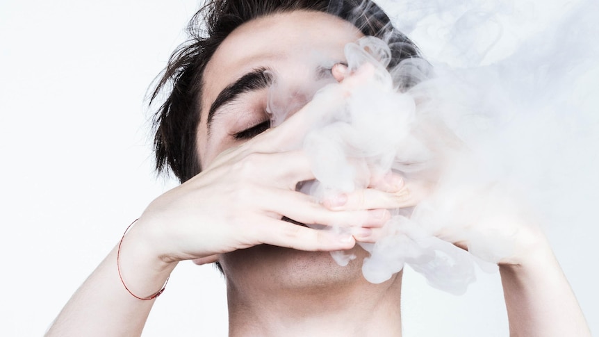 young man vaping with two hands in front of face