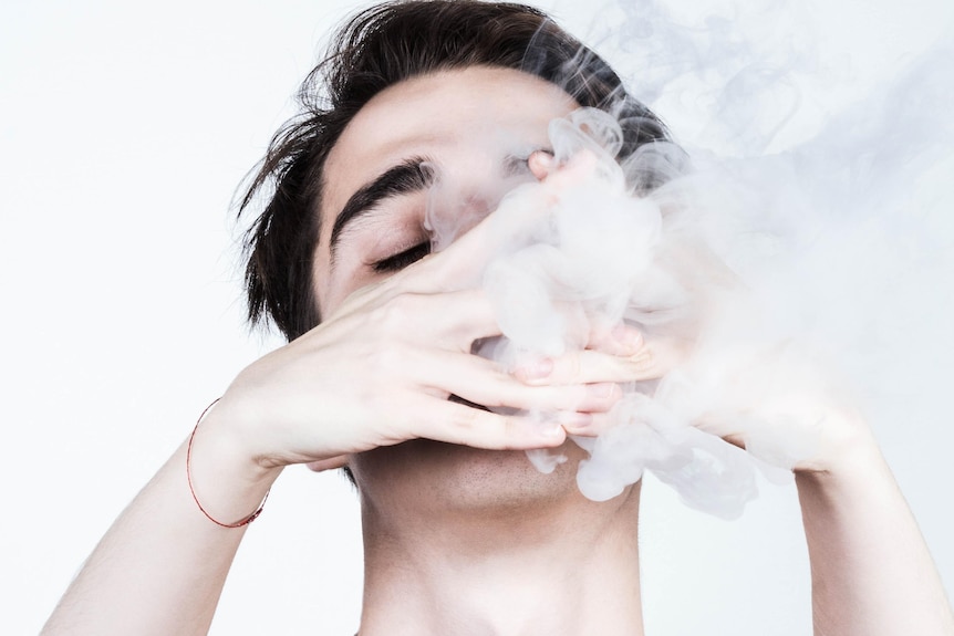 young man vaping with two hands in front of face