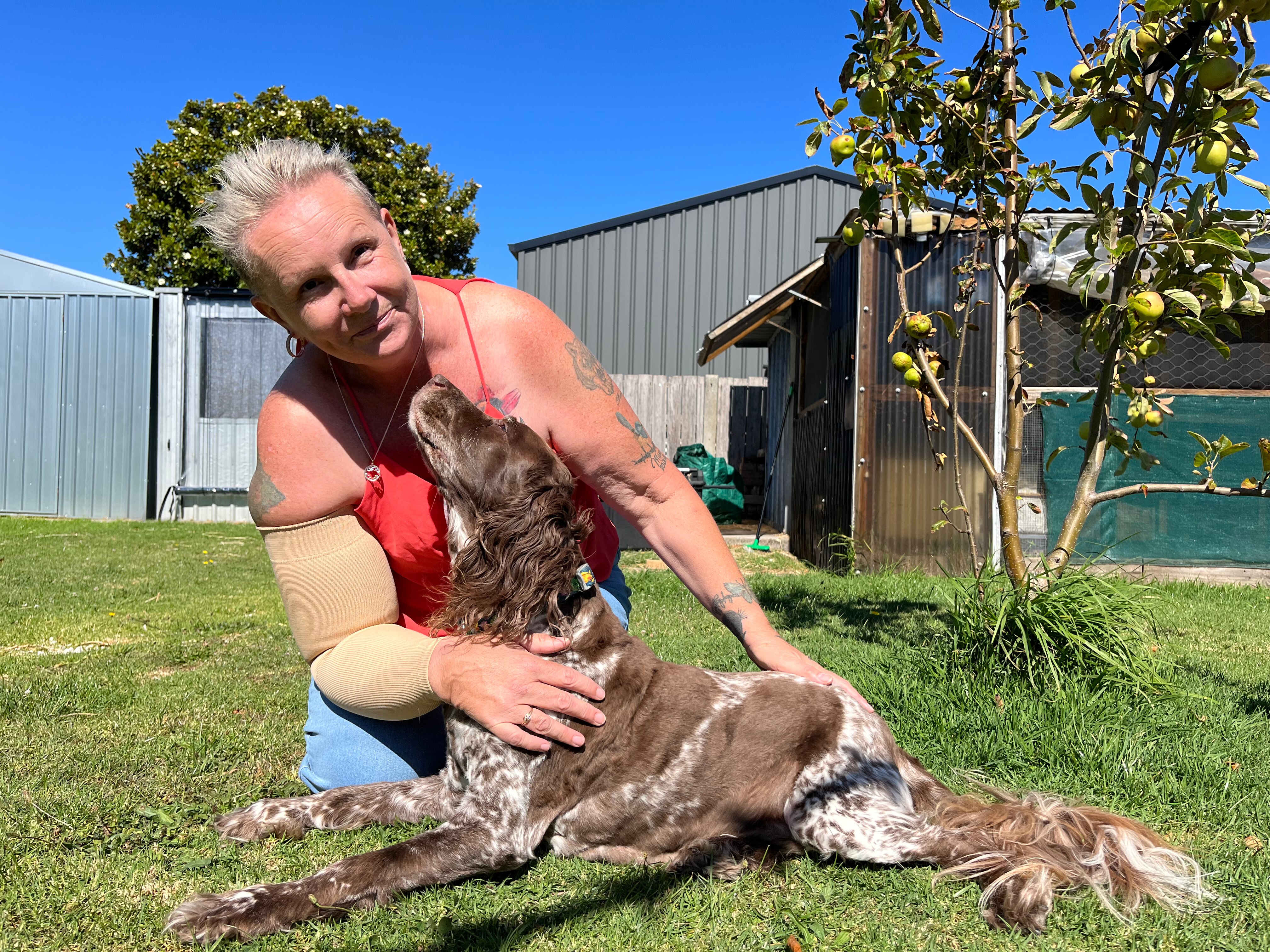 Sue Kole in her backyard hugging her dog