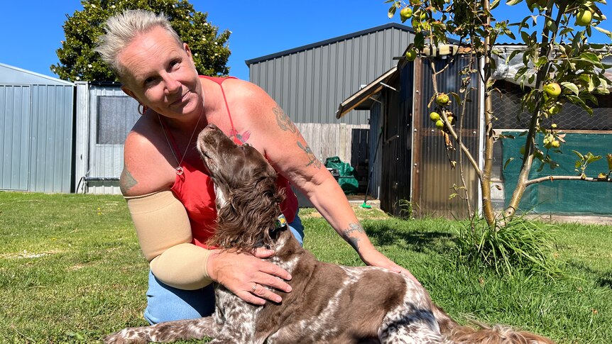 Sue Kole in her backyard hugging her dog