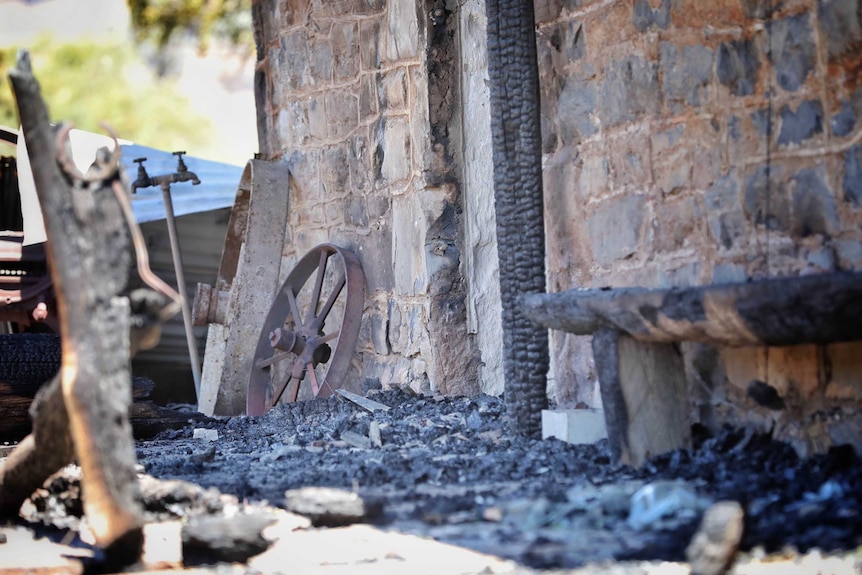 Ashes and burnt-out embers in front of a building after a fire.